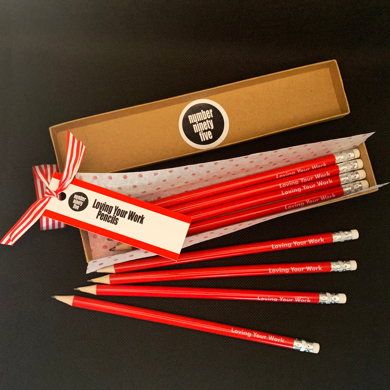 Number Ninety Five, Loving Your Work, 8 sharpened red pencils with white rubber tips, gift wrapped in a kraft box, with 8 pencils stating the phrase Loving Your Work written on them in white text.