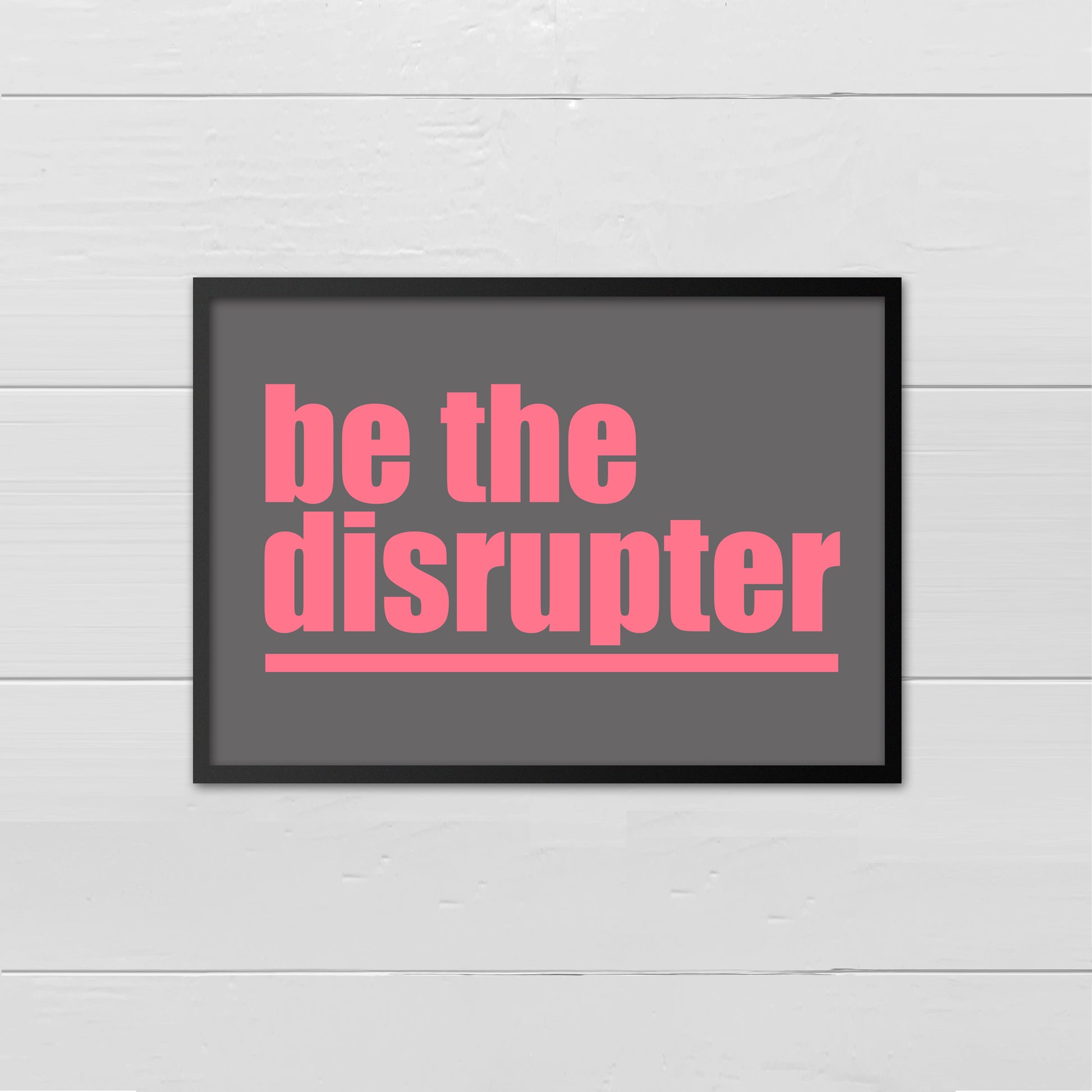 Landscape style print with the words Be The Disrupter underlined and written in pink onto a dark grey back ground